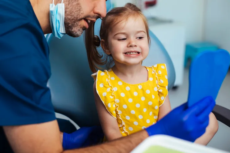 Young girl looking at a mirror after having a routine checkup at the dentist